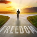 A person stands at a T junction, just in front of the word 'Freedom' written on the road